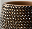 Close-up of a ceramic plant pot covered with faceted round brown smoky glass crystals, showing the warm brown interior and reflective surfaces.
