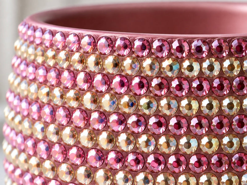 Close-up of a pink cylindrical plant pot covered with rows of faceted crystals in pink, champagne, and iridescent tones.