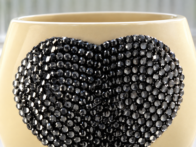 A close-up of a cream-colored ceramic  planter decorated with a large grey heart-shaped embellishment covered in faceted grey rhinestones.