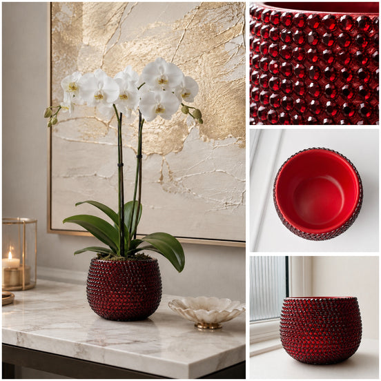 A red textured ceramic pot shown covered with red crystal stones shown in a styled interior scene with white orchids on a marble surface, plus close-up inset views of the pot's textured exterior, red interior, and the pot by a framed abstract canvas print.