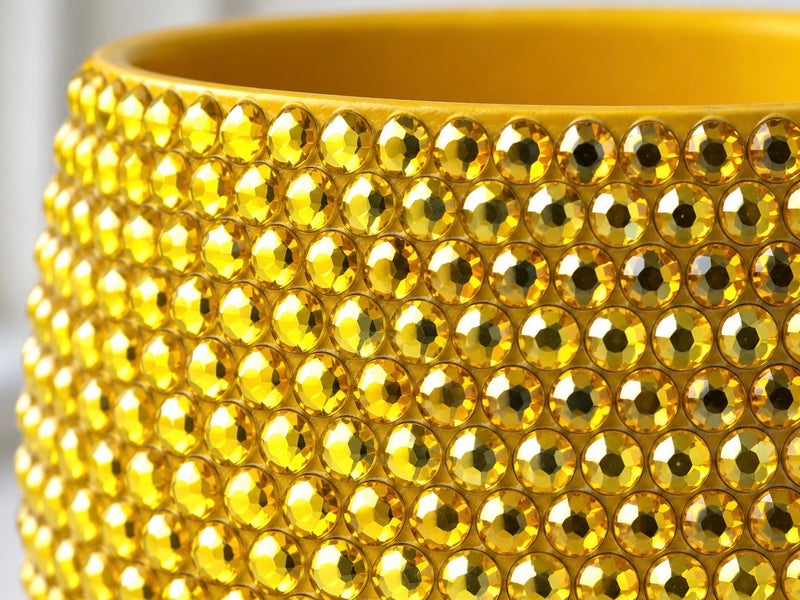 Close-up of a yellow  planter covered with rows of faceted yellow crystals, showing the glossy reflective surface and bright yellow color.