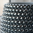 Close-up of a grey Moon Dust planter covered with faceted dark grey to black crystals, showing the reflective crystal texture in detail.