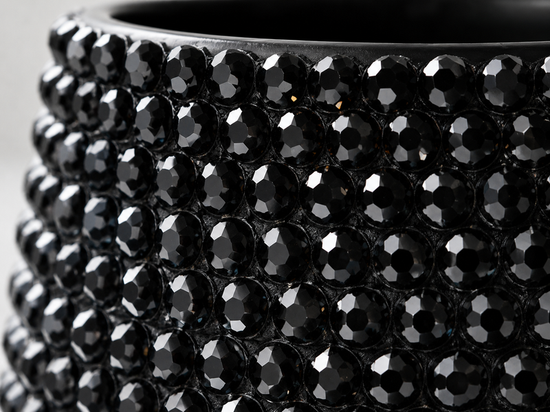 Close-up of a glossy black faceted gemstone-covered ceramic plant pot,, showing rows of round black crystals on a dark base.