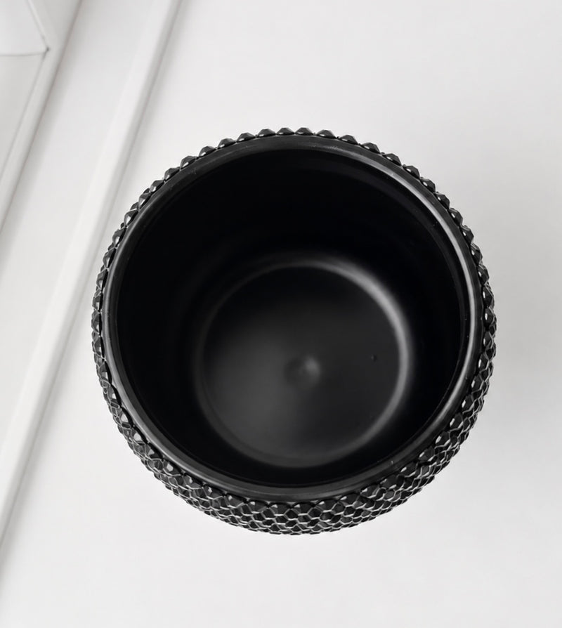 A black ceramic plant pot with a textured, beaded outer rim, shown from a top-down perspective on a clean white background.