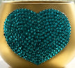 A heart-shaped decorative embellishment covered in teal blue rhinestones, attached to a gold-colored plant pot.