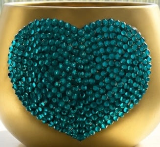 A heart-shaped decorative embellishment covered in teal blue rhinestones, attached to a gold-colored plant pot.