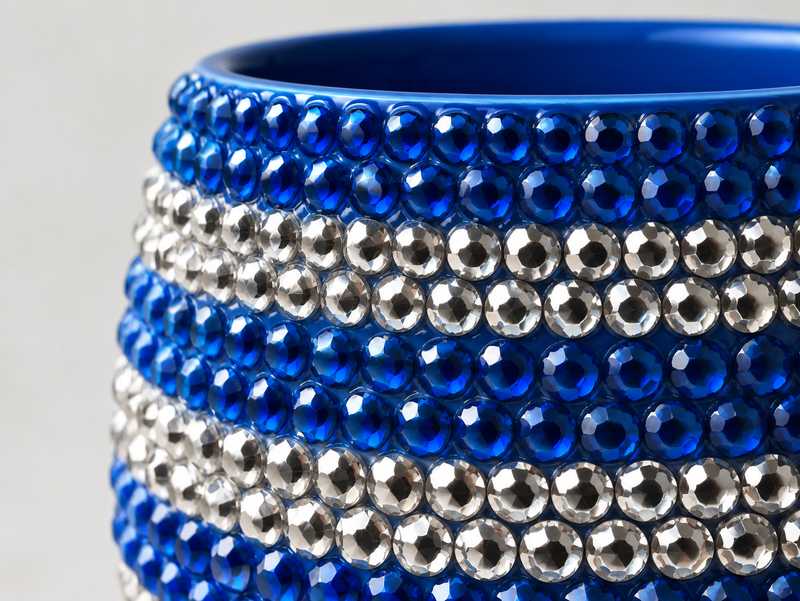 Close-up of a ceramic plant pot decorated with horizontal rows of faceted blue and silver crystals.