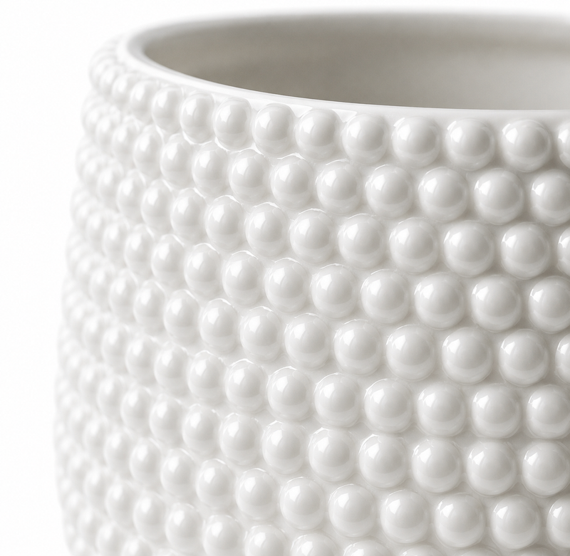Close up shot of a white ceramic plant pot showing its textured surface and pearl accents. 