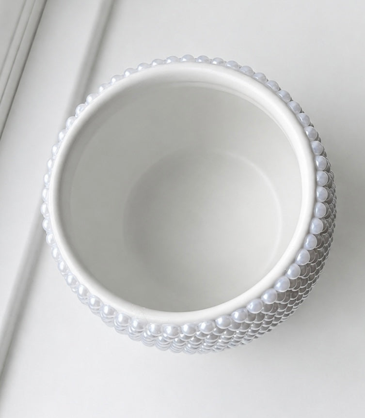A white ceramic bowl with a textured, beaded outer rim, photographed from a top-down angle on a clean white surface.