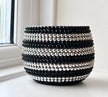 A round black and silver planter decorated with horizontal rows of faceted black and silver crystals, set on a windowsill.