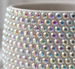 Close up shot of a white ceramic plant pot covered with sparkling iridescent crystals. 