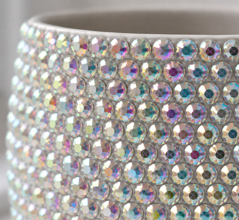 Close up shot of a white ceramic plant pot covered with sparkling iridescent crystals. 